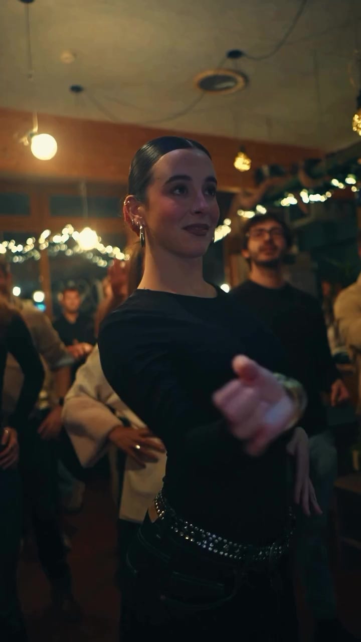 A flamenco dancer dancing among the crowd under string lights at El Payo.